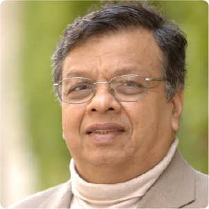 A color photo of a man with glasses wearing a turtleneck and jacket