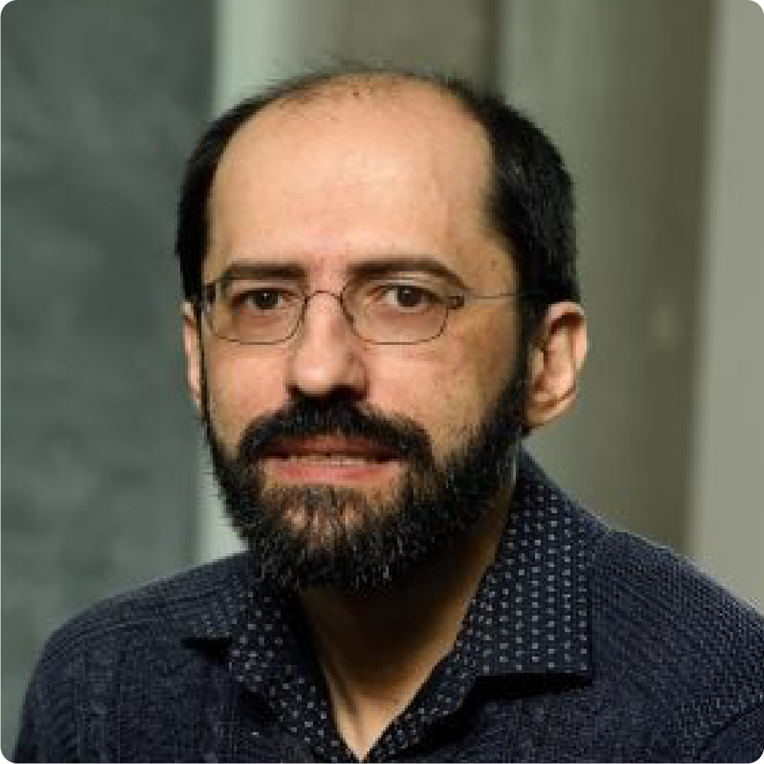 A color photo of a man with glasses and a beard.