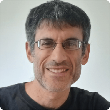 A color photo of a man with glasses, smiling for a photo.