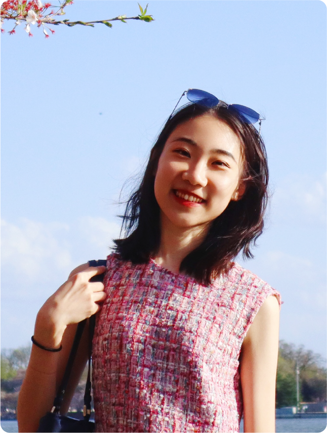 A color photo of a woman outside, smiling for a photo.