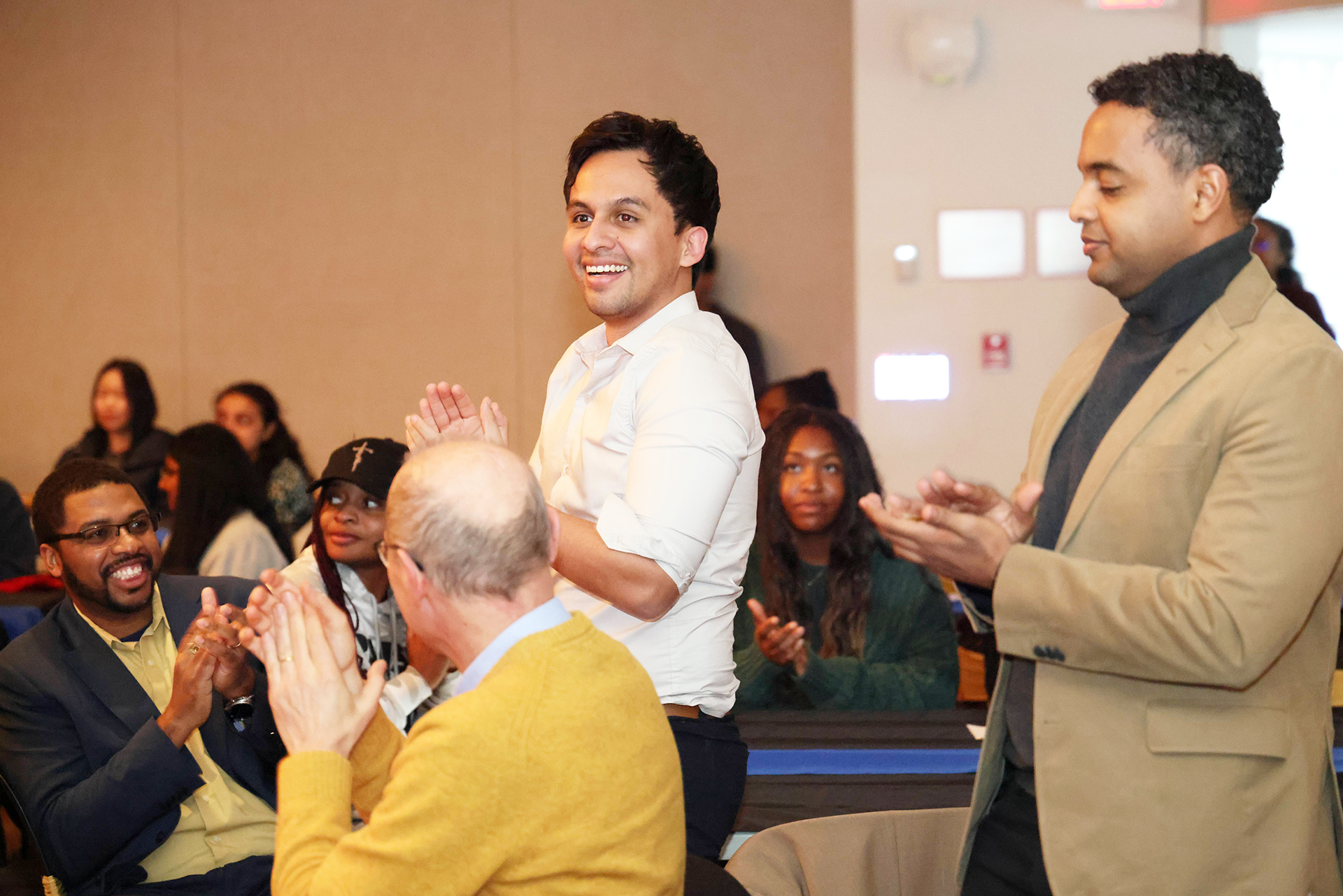 A color photo showing people clapping at an event.
