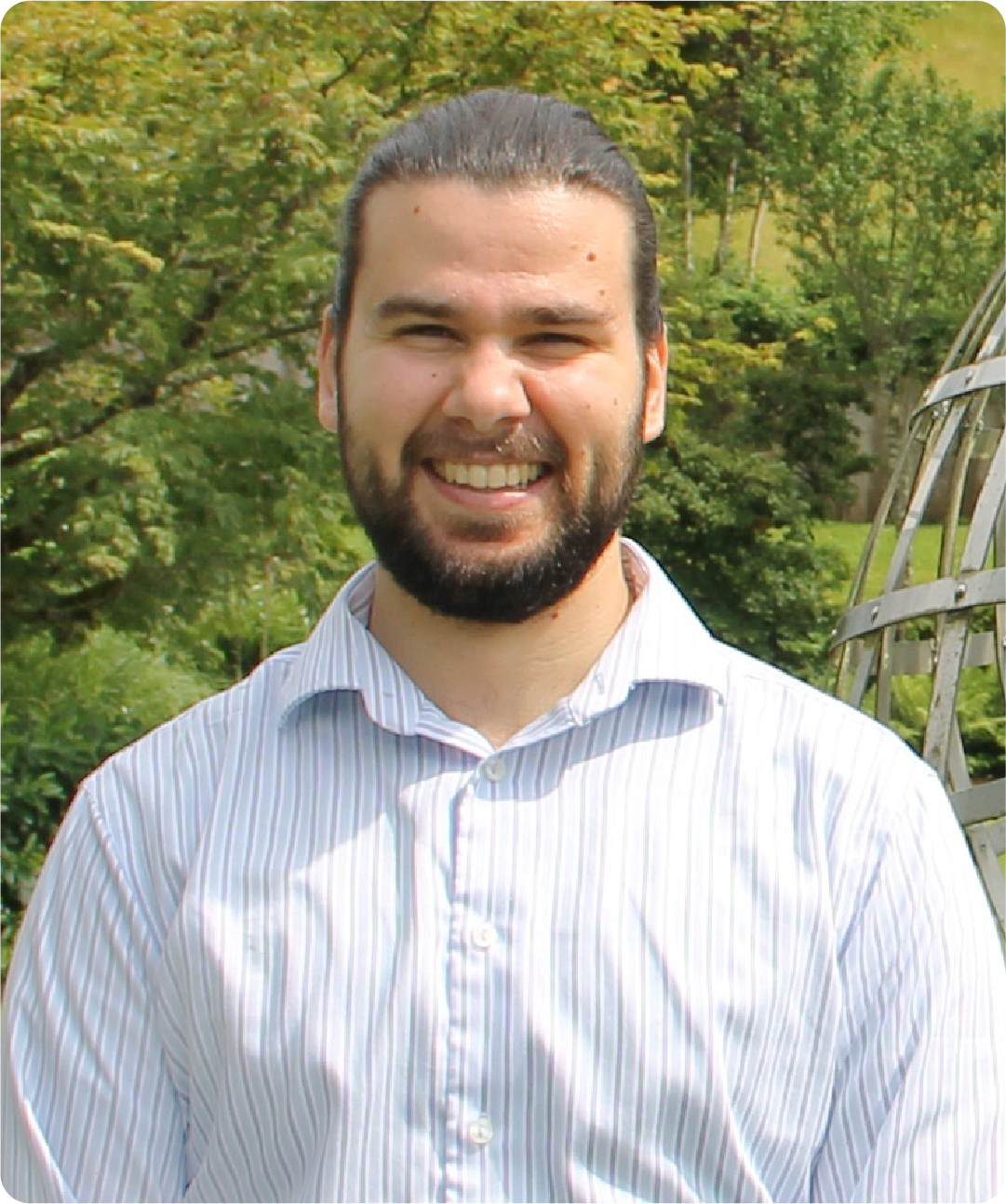 A color photo of a man in a dress shirt smiling for a photo.