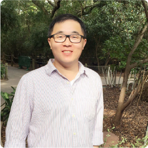 A color photo of a man smiling for a photo outdoors.