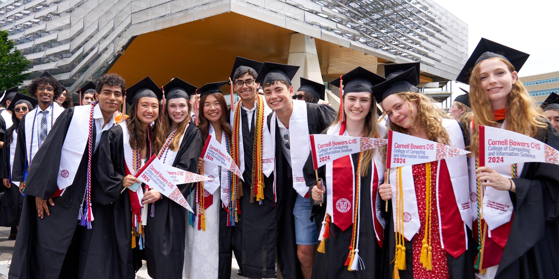 Group of students with pennants and in graduation regalia celebrating	