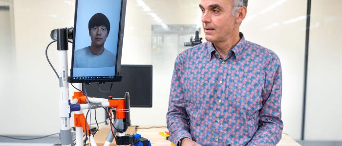 man in colorful shirt holding a remote that controls a tablet on a platform
