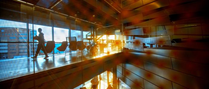 people walking along hallways, sun setting, reflected in glass
