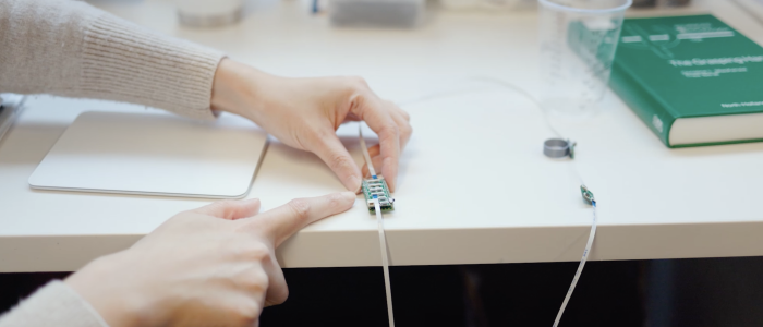 two hands touch a wire and piece of tech