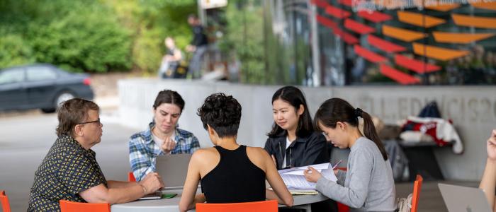 Group of people sitting at table outside Gates Hall