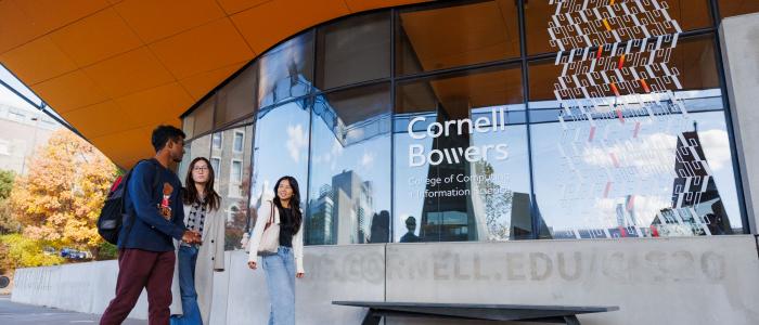 three students walk in front of Gates Hall