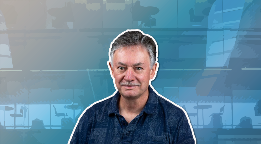 A color photo of a man smiling for a photo with blue background