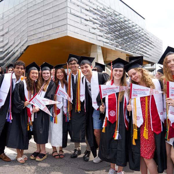 Group of students with pennants and in graduation regalia celebrating	