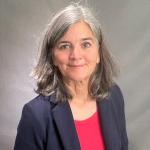 Color portrait of woman with long grey hair in a suit, looking at camera
