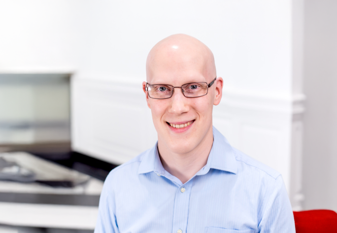 A color photo of Tyler Wilcox smiling for a photo