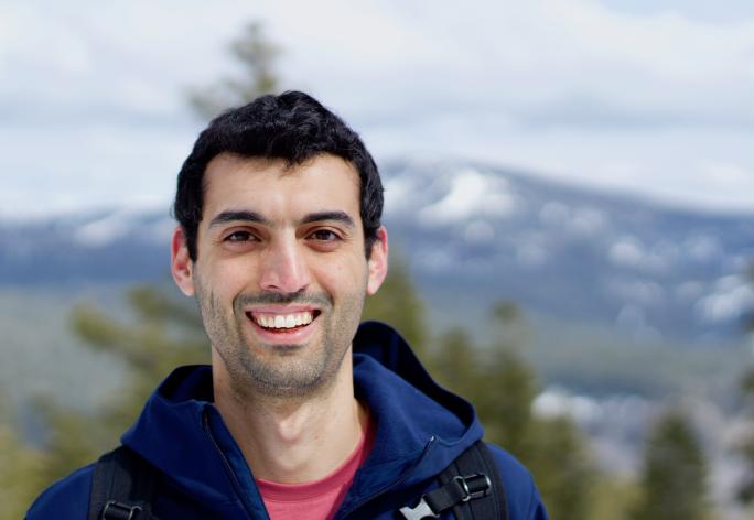 color portrait of man with dark hair on mountain, smiling