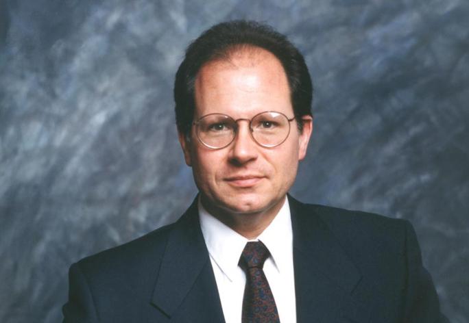 color portrait of man in suit, dark short hair, wire framed glasses