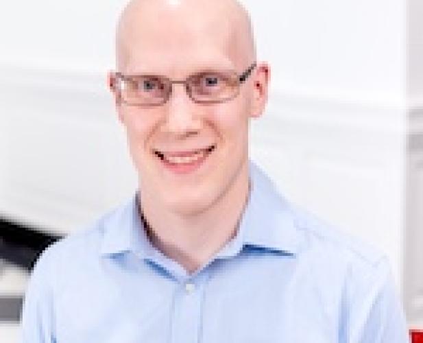 a bald man with glasses wearing a light blue button down shirt