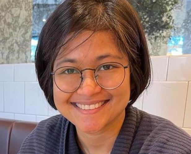 Color photo of woman with chin length black hair, round wire framed glasses