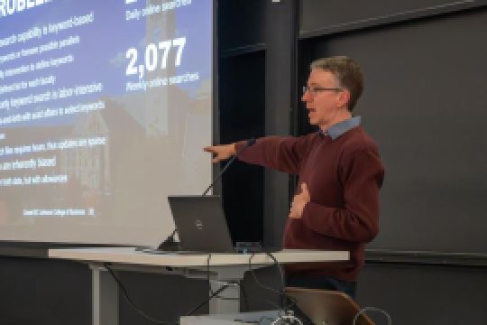 A color photo of a man giving a presentation. by Luke Stewart - Cornell Bowers