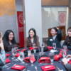 A color photo of people seated at a table, speaking to each other