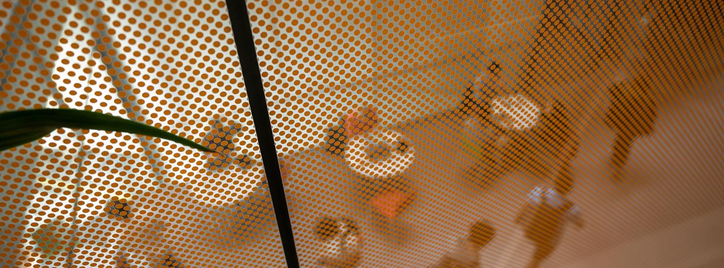  image of the inside of Gates Hall atrium looking down from the second floor, shot through reflection of glass